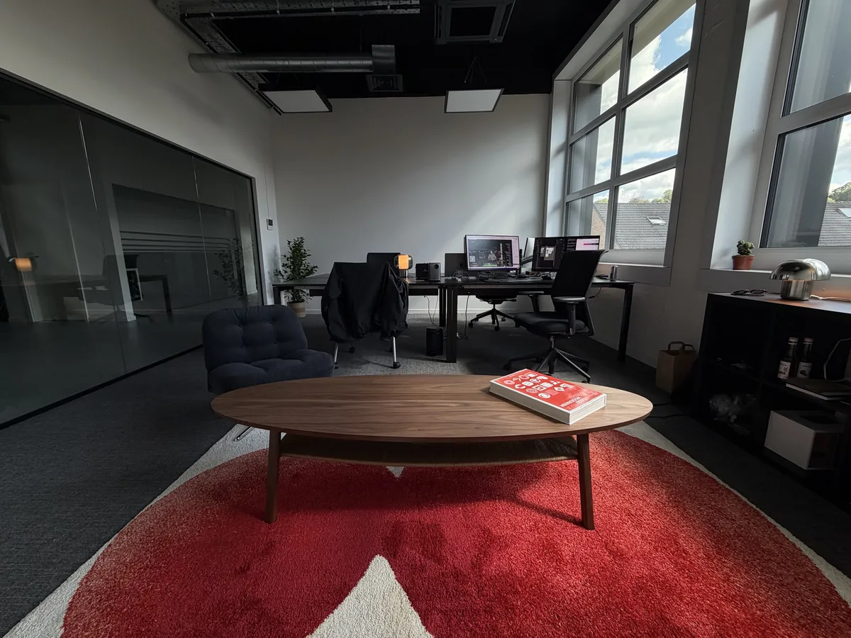 Le studio Initial : table basse, tapis rouge et postes de travail sous la verrière