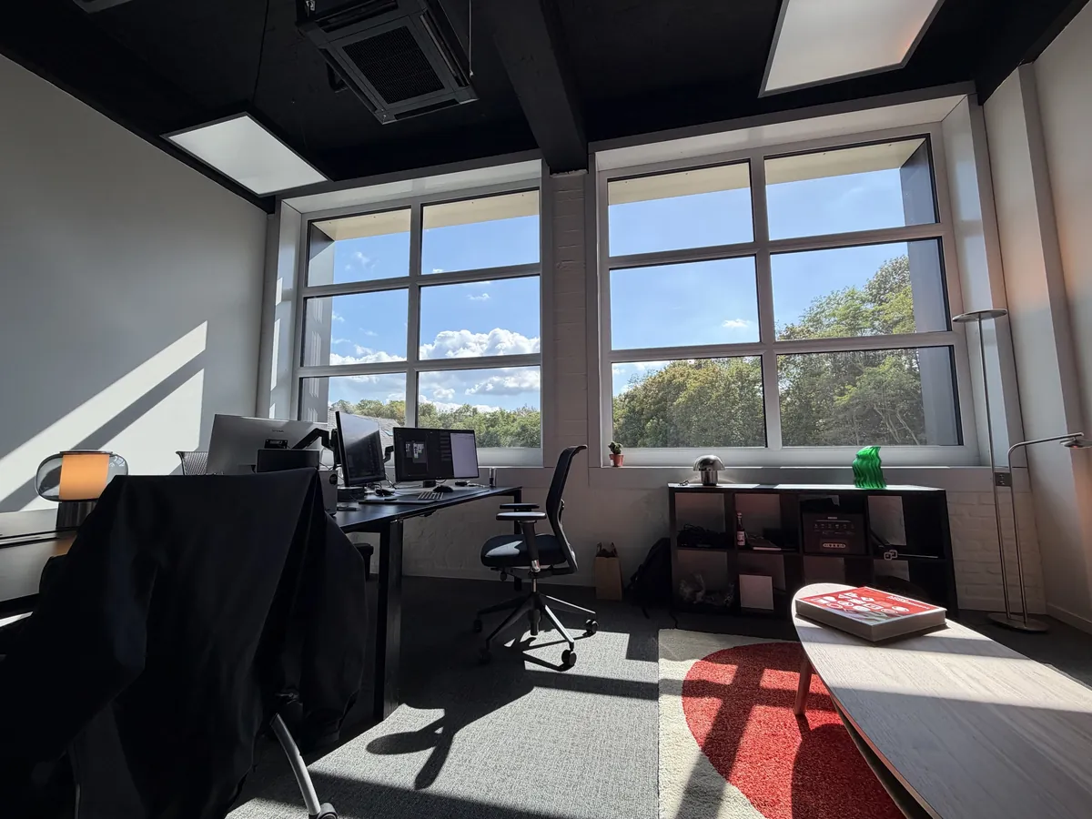 Le studio Initial : bureaux face aux grandes fenêtres donnant sur les arbres